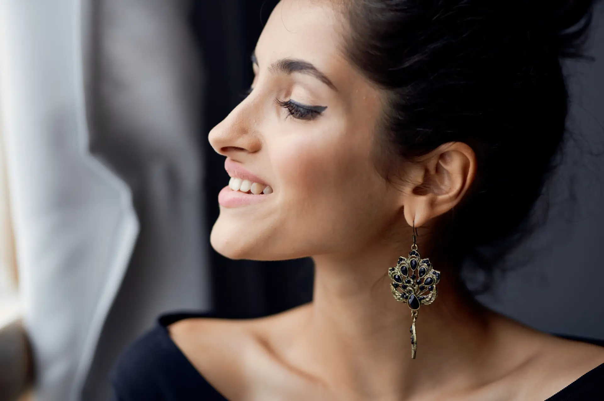 Dama elegante en interiores, cerca de una ventana, modelo en un ambiente con cortinas grises.